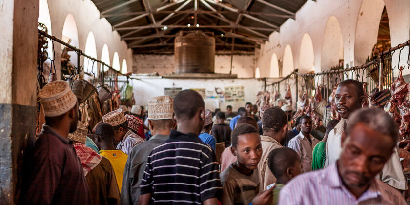 People in a crowded Darajani market in Zanzibar City, some wearing bargashia (traditional hats similar to the kofia).