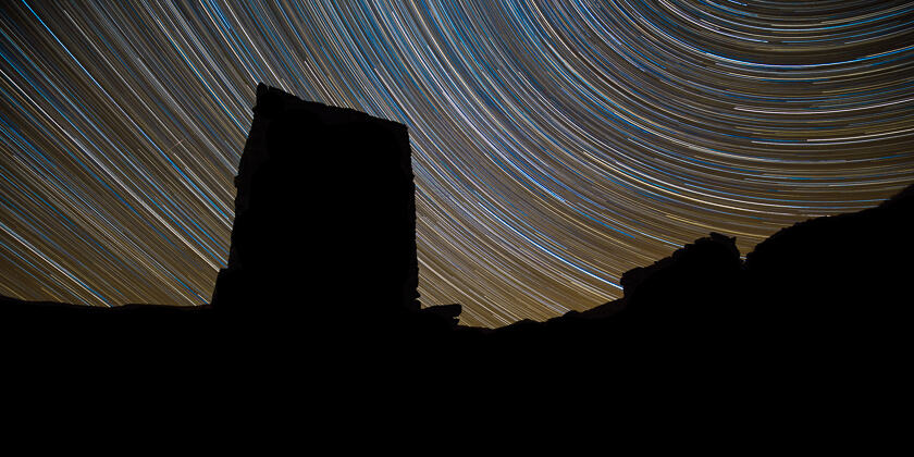 Star trails and shooting star in the Lake District, with a disused mine shaft tower in silhouette.
