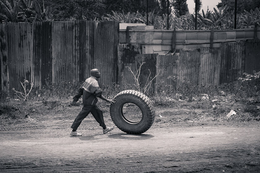 A man rolling a huge tyre along a dust road in Arusha, Tanzania. 