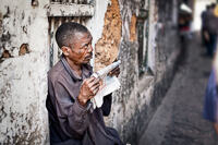 A Zanzibari man looking up from his newspaper in a Stone Town alley.