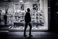 A man wearing Converse shoes walking past a shoe shop on Oxford Street at Christmas.